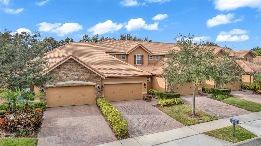 A multi-unit residential building with tan stucco, stone accents, and a tiled roof — 10345 BELFRY CIRCLE, ORLANDO, FL