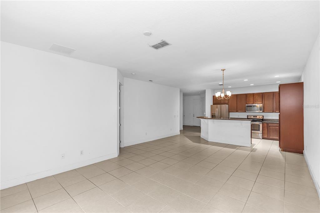 An open-concept kitchen with wood cabinets and a breakfast bar overlooks a tiled living area — 10345 BELFRY CIRCLE, ORLANDO, FL