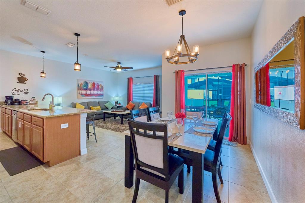 An open-concept kitchen, dining area, and living room featuring tile floors and a sliding door — 4821 BRIER ROSE LANE, KISSIMMEE, FL