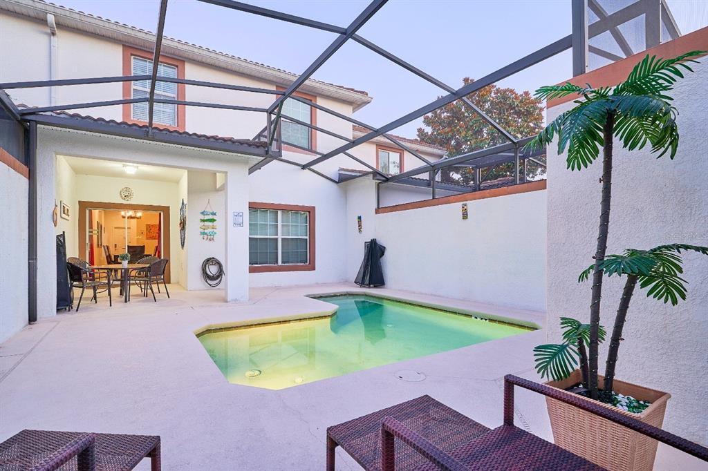 A screened-in patio features a small swimming pool, lounge chairs, and a covered dining area — 4821 BRIER ROSE LANE, KISSIMMEE, FL