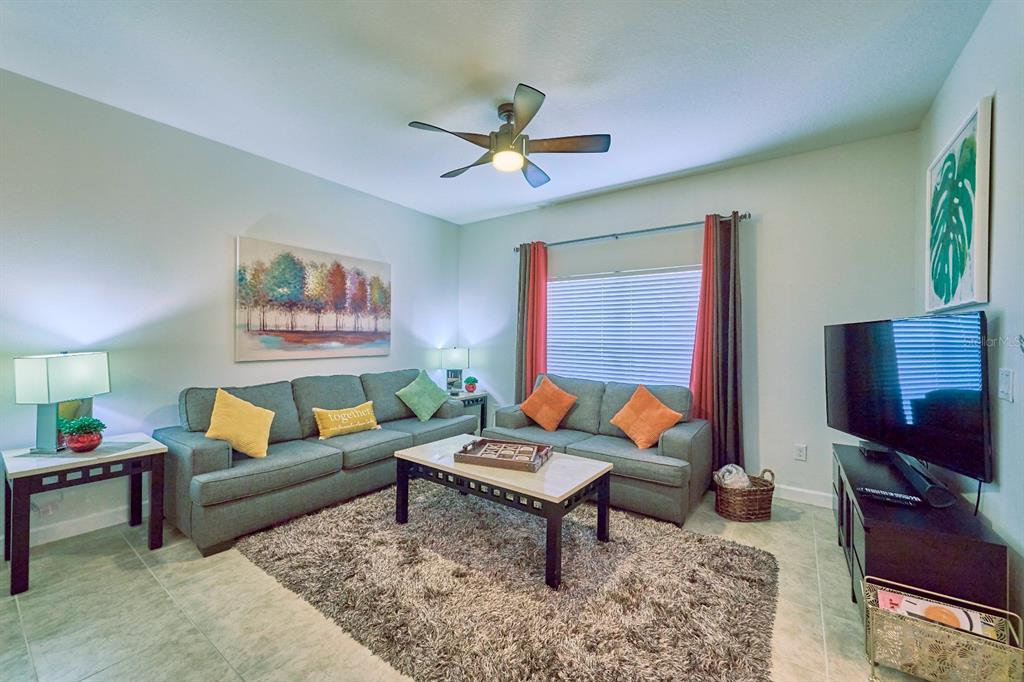A living room features two teal sofas, a coffee table, and a large area rug — 4821 BRIER ROSE LANE, KISSIMMEE, FL