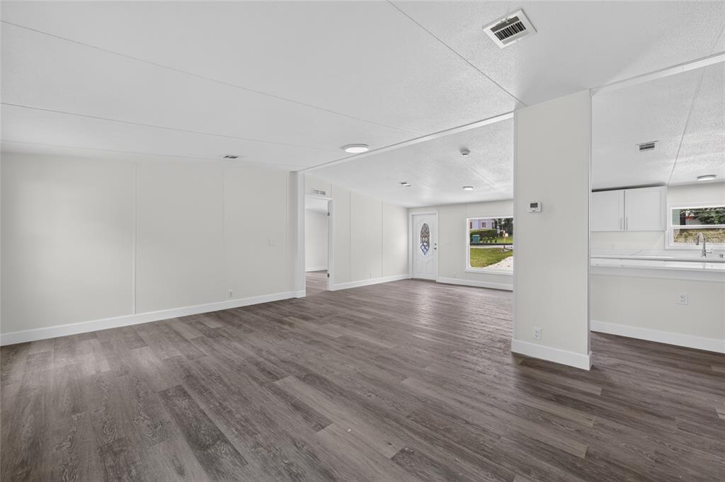 An open-concept living area features light-colored walls, dark wood-look flooring, and a white kitchen — 225 SKYLINE DRIVE, LADY LAKE, FL