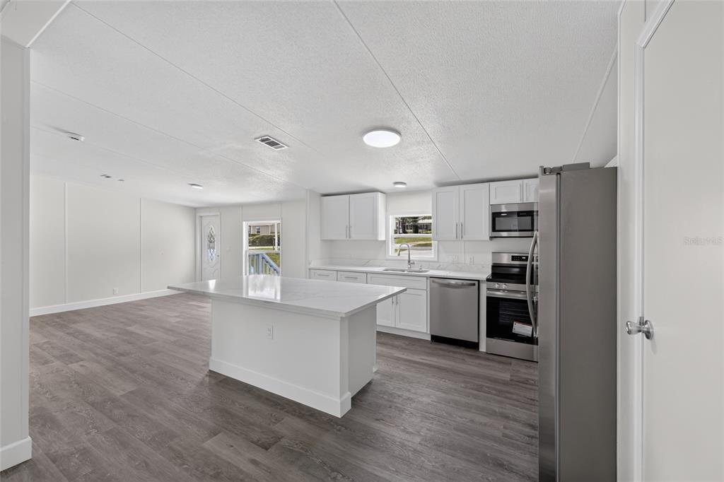 A modern kitchen features white cabinets, a central island, and stainless steel appliances — 225 SKYLINE DRIVE, LADY LAKE, FL