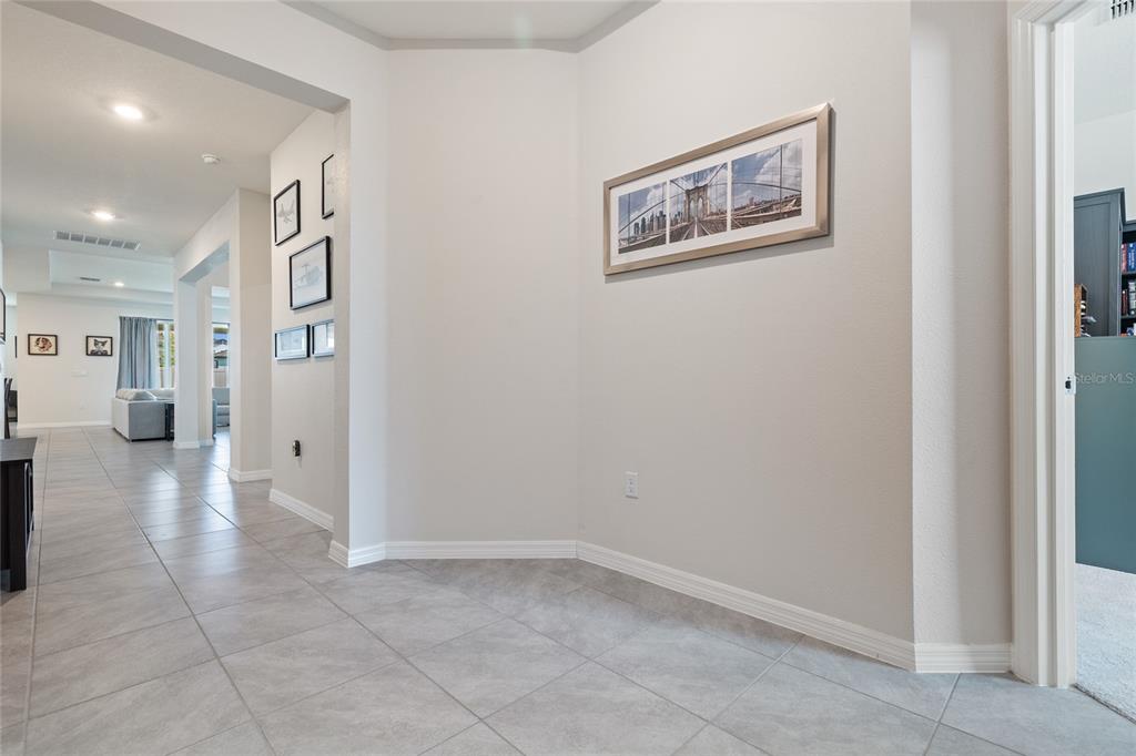 A tiled hallway leads to an open living area with framed wall art — 12401 SHINING WILLOW STREET, RIVERVIEW, FL