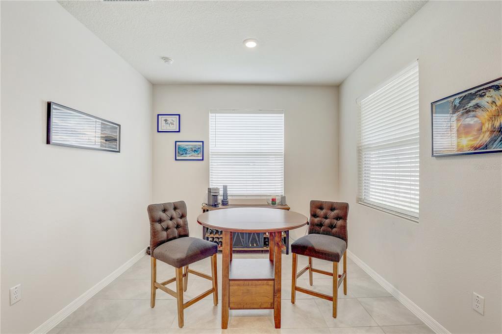 A dining area features a round wooden table, two tufted chairs, and two windows — 12401 SHINING WILLOW STREET, RIVERVIEW, FL