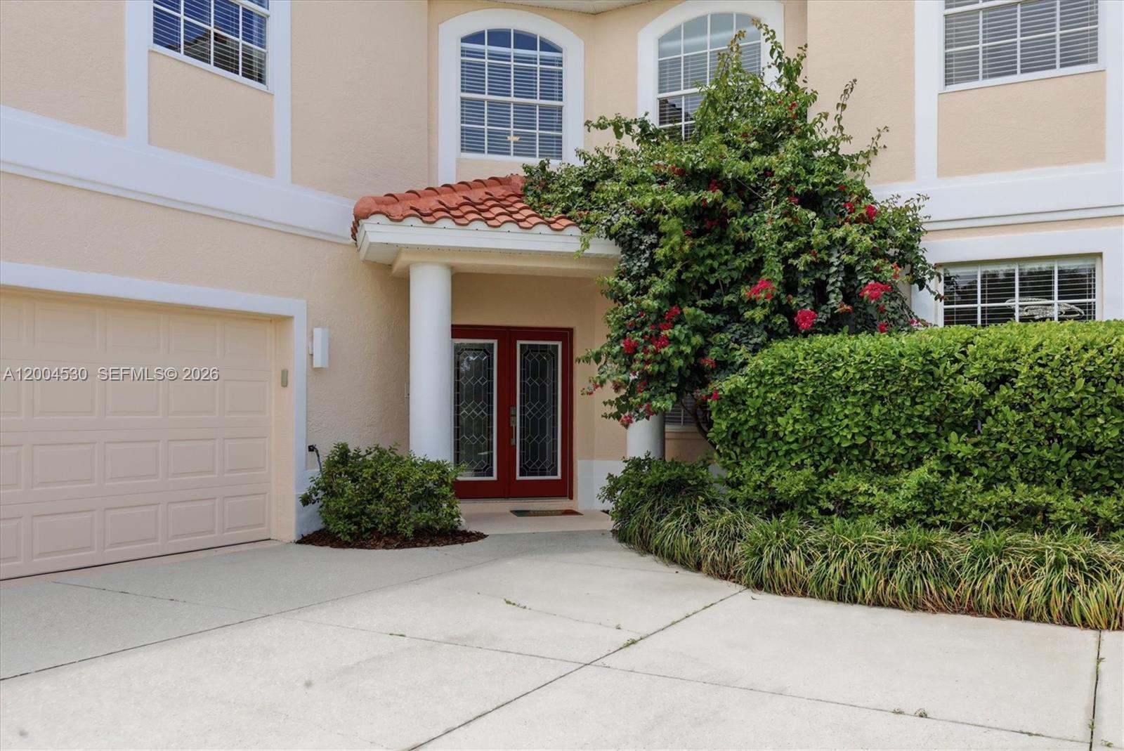 The exterior of a two-story house features a red double door, garage, and landscaping — 674 Clear Creek Drive, Sarasota FL 34229, SARASOTA, FL