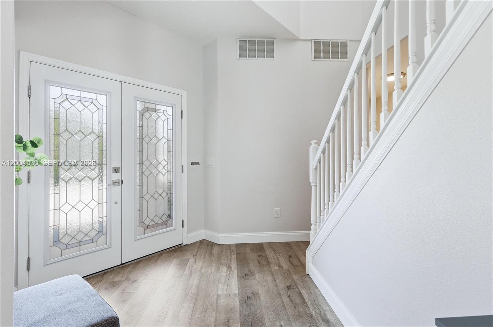 An entryway features a double glass-paneled door, light wood-look flooring, and a white staircase — 674 Clear Creek Drive, Sarasota FL 34229, SARASOTA, FL