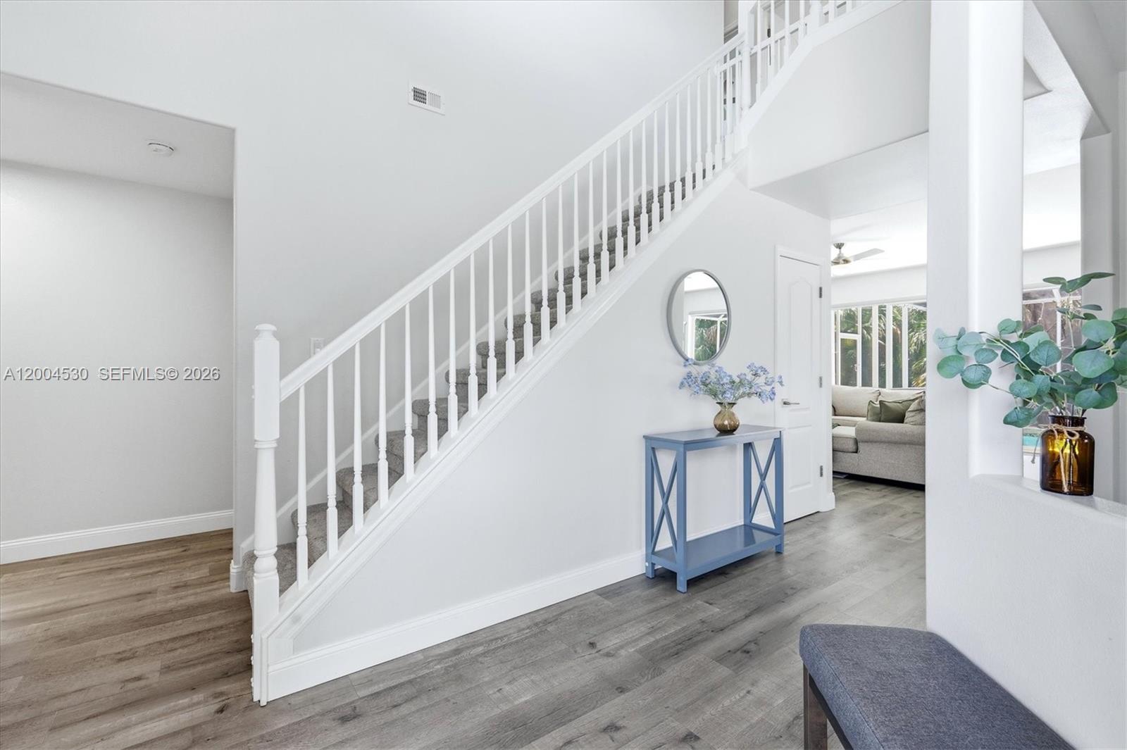 A bright entryway features a carpeted staircase, a blue console table, and wood-look flooring — 674 Clear Creek Drive, Sarasota FL 34229, SARASOTA, FL