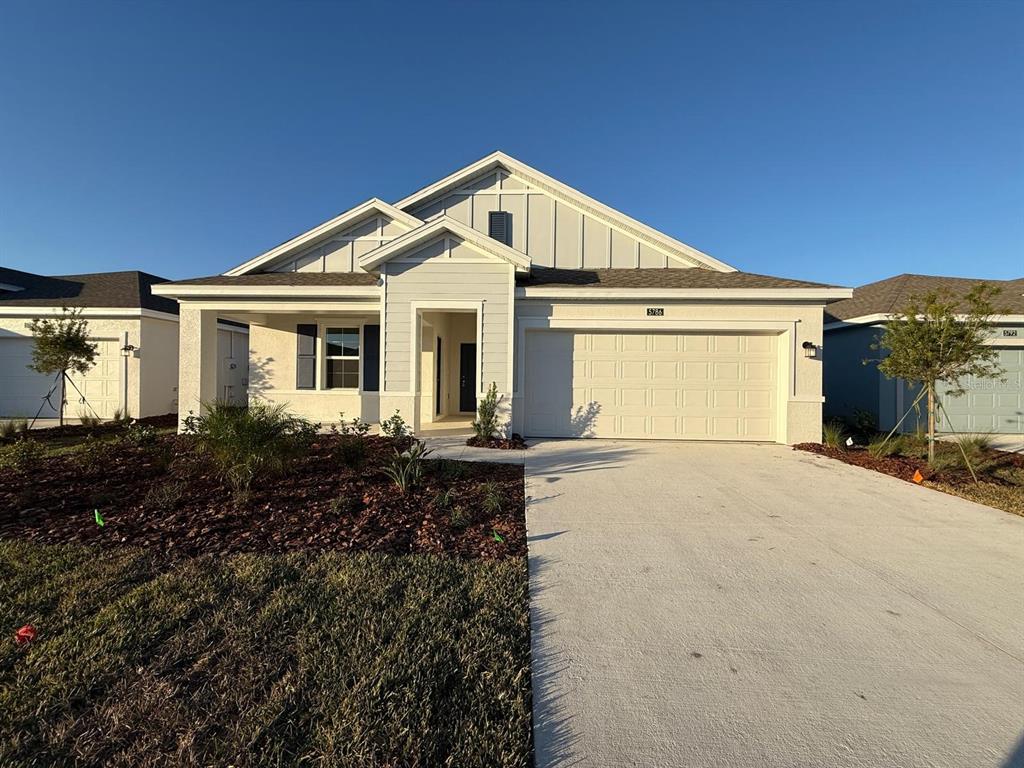 A single-story house with a light-colored facade, a two-car garage, and a covered entryway — 5786 GINGHAM DRIVE, KISSIMMEE, FL