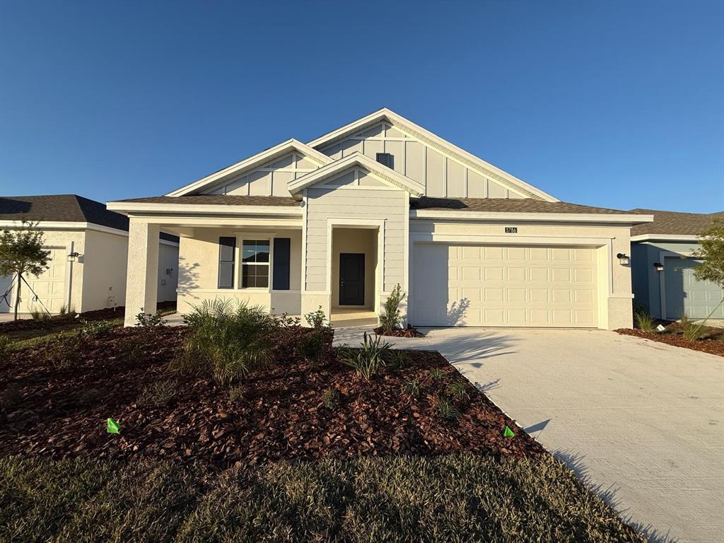 A single-story house with light gray siding, a two-car garage, and a front porch — 5786 GINGHAM DRIVE, KISSIMMEE, FL