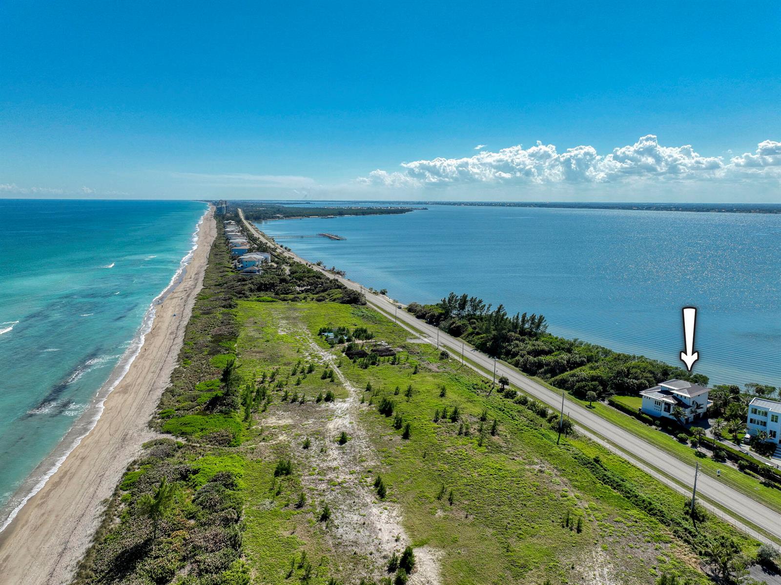 An aerial view shows a house situated between a beach and a large body of water — 7683 Pelican Pointe Drive, Jensen Beach FL 34957, JENSEN BEACH, FL
