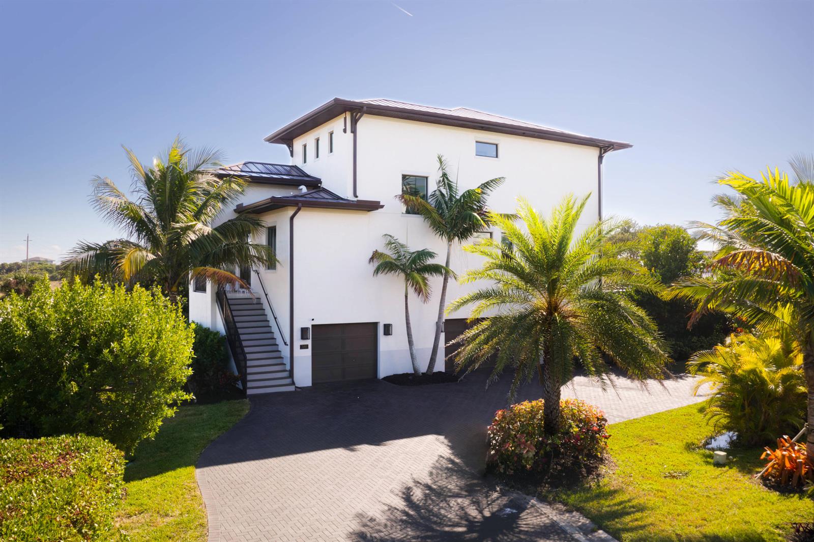 A three-story white house with a dark roof, a paved driveway, and several palm trees — 7683 Pelican Pointe Drive, Jensen Beach FL 34957, JENSEN BEACH, FL