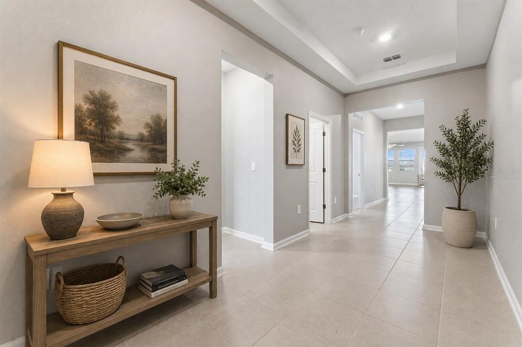 A bright, tiled hallway features a console table with decor and a potted plant — 3012 NAMASTE DRIVE, CLERMONT, FL