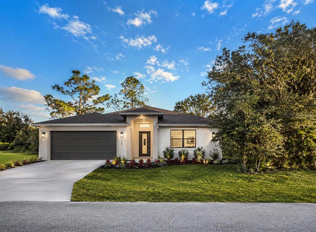 A single-story house with a white stucco exterior, dark garage door, and a front lawn — 1336 HILLSBOROUGH COURT, POINCIANA, FL