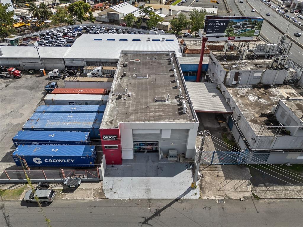 An aerial view shows a commercial building with shipping containers and a large billboard nearby — 168-198 CALLE MONTERREY, SAN JUAN, PR