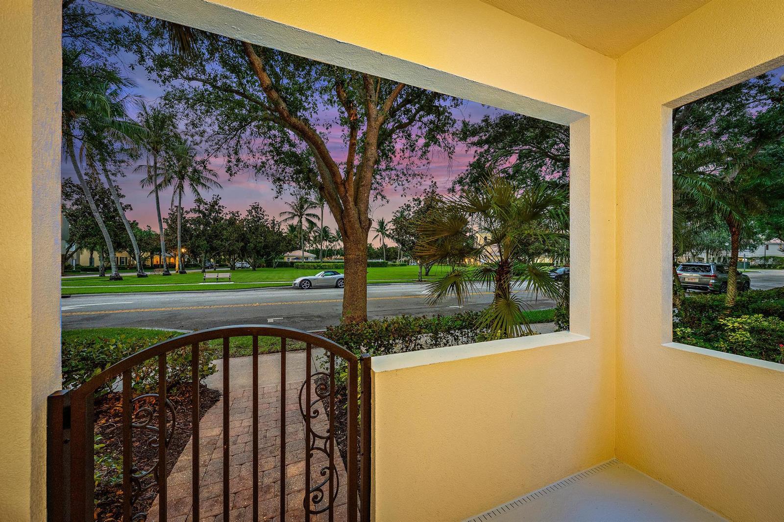 A view from a covered porch looking out toward a street, trees, and a sunset — 1856 Jeaga Drive, Jupiter FL 33458, JUPITER, FL
