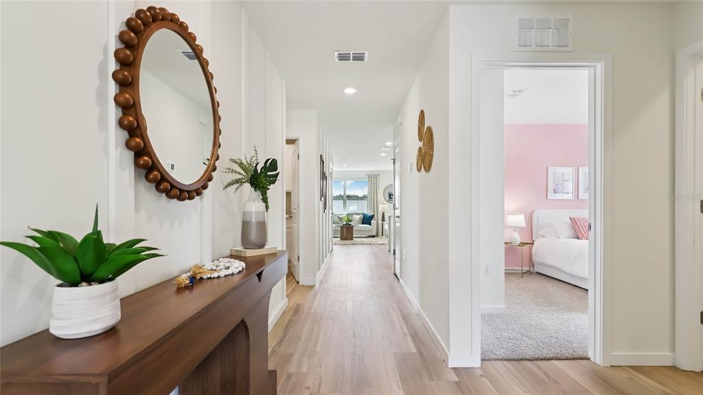 A hallway with light wood floors leads to a living area, with a bedroom visible — 11008 NW 167TH TERRACE, ALACHUA, FL