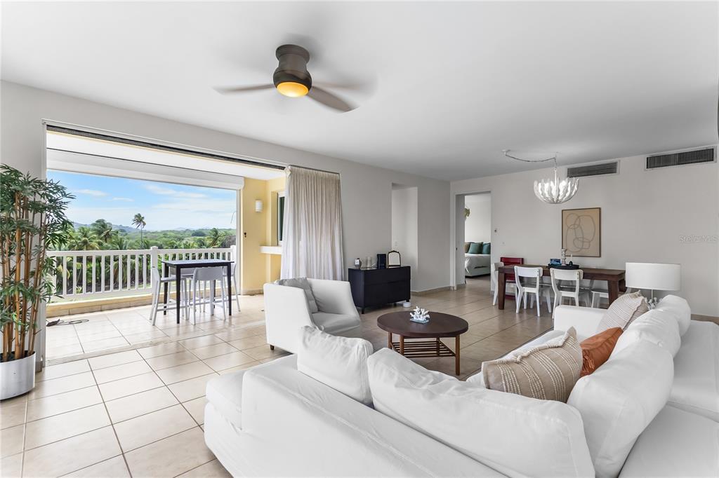 A bright living room with white furniture, tile floors, and a balcony overlooking tropical scenery — 500 OCEAN DRIVE UNIT 535, HUMACAO, PR