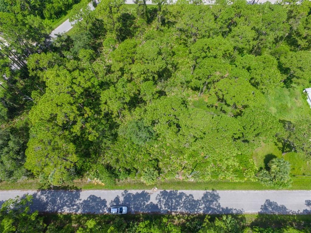 An aerial view shows a wooded, undeveloped rectangular lot bordering a paved road — LOTS 15,16,17 TEGASTAS STREET, NORTH PORT, FL