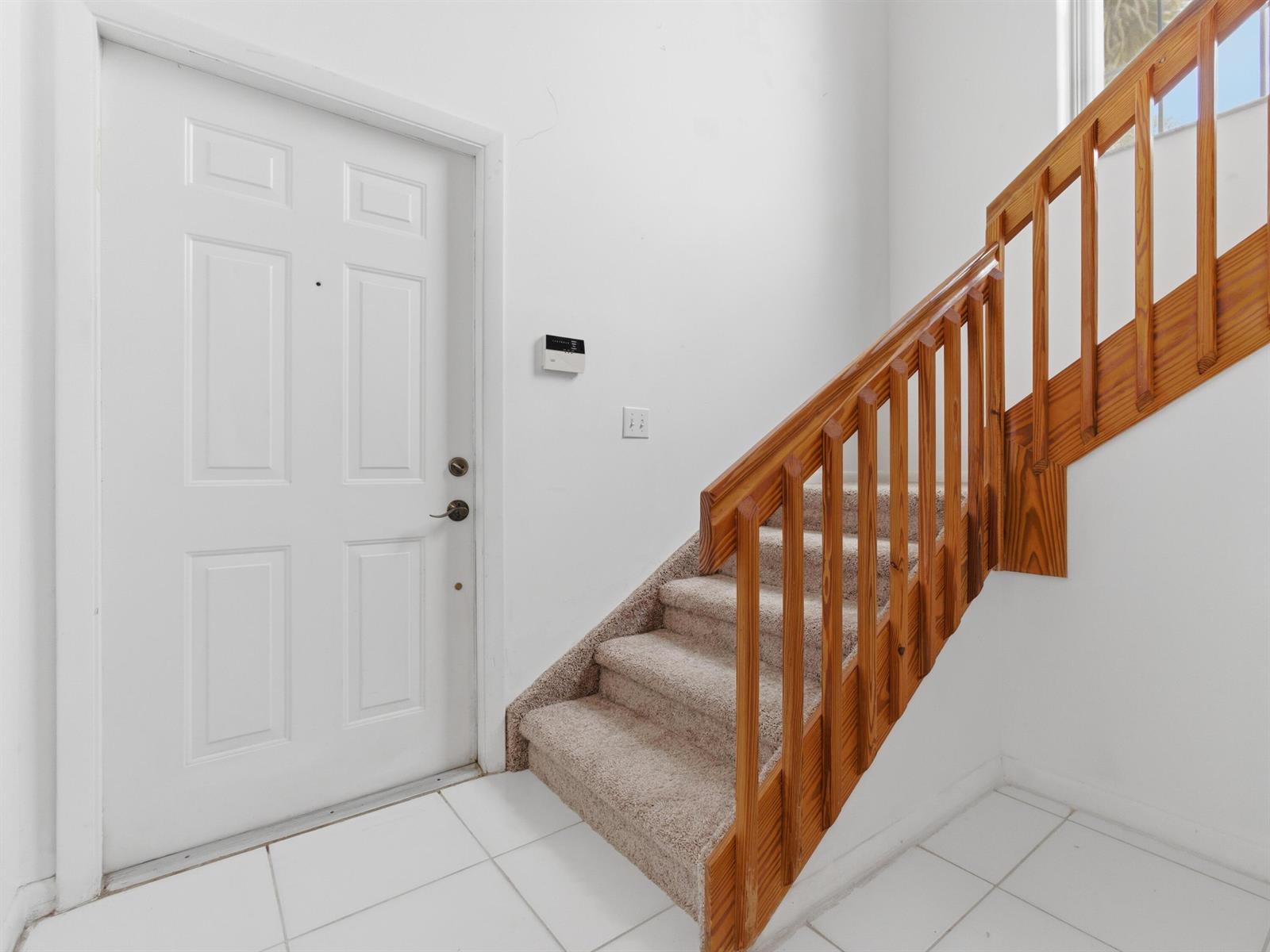 A white front door sits next to a carpeted staircase with a wooden railing — 14383 Via Royal # 3, Delray Beach FL 33446, DELRAY BEACH, FL