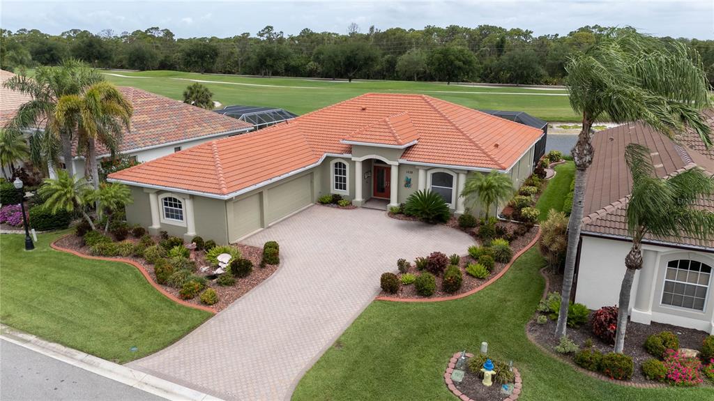 An aerial view of a single-story house with a tile roof and a paved driveway — 1038 TUSCANY BOULEVARD, VENICE, FL