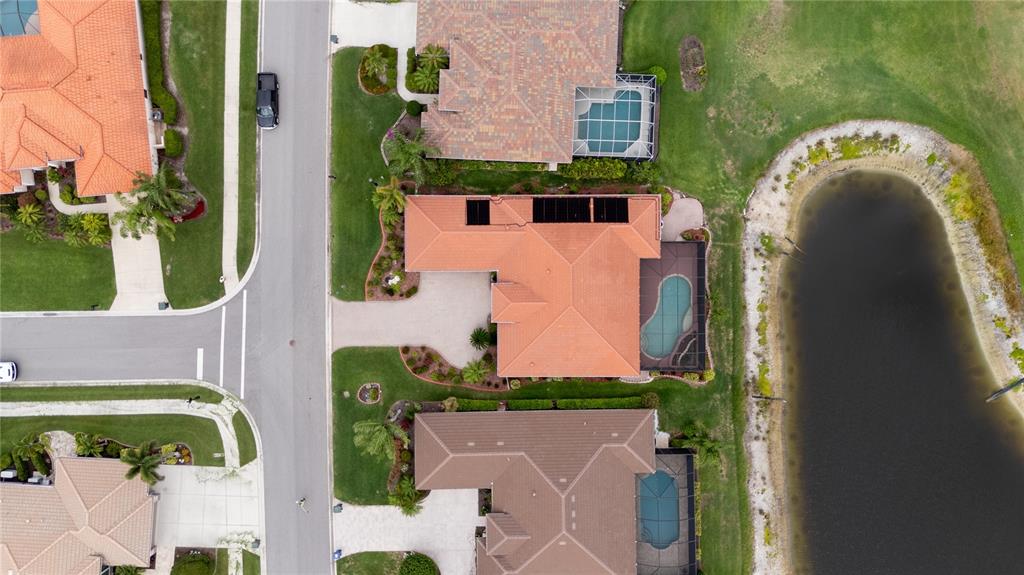 An aerial view shows a suburban house with a tiled roof, pool, and solar panels — 1038 TUSCANY BOULEVARD, VENICE, FL