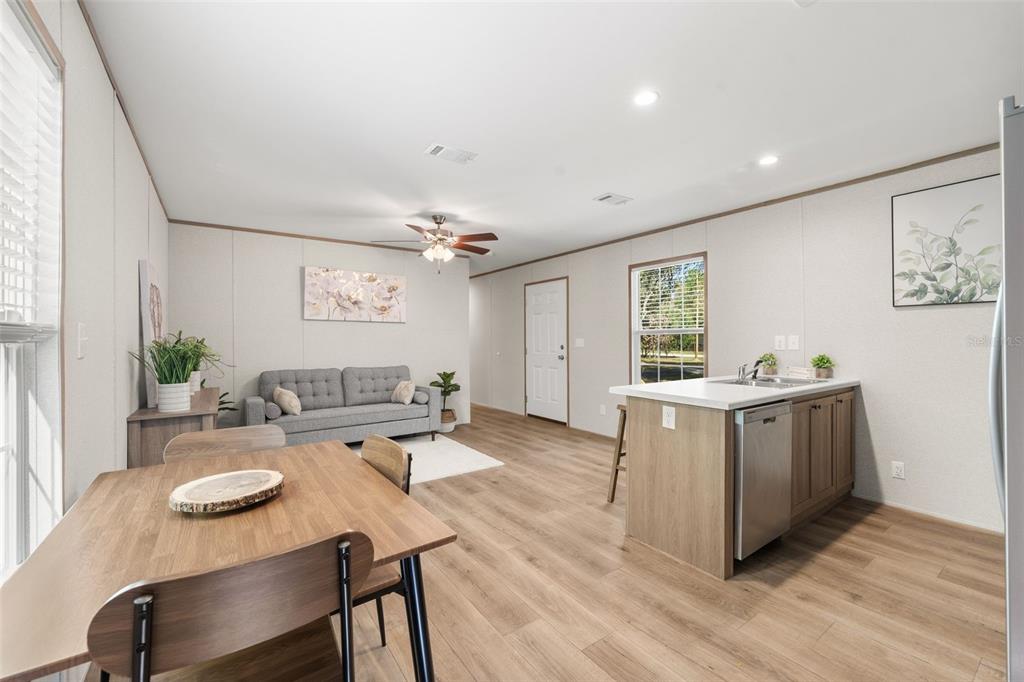 An open-concept living and dining area features light wood flooring, a kitchen island, and furniture — 10970 NE 71ST STREET, BRONSON, FL