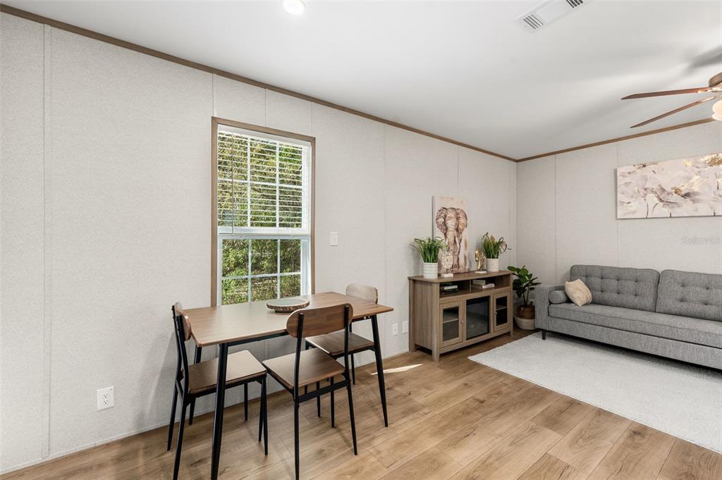 A living and dining area features light-colored walls, wood-look flooring, a sofa, and a table — 10970 NE 71ST STREET, BRONSON, FL