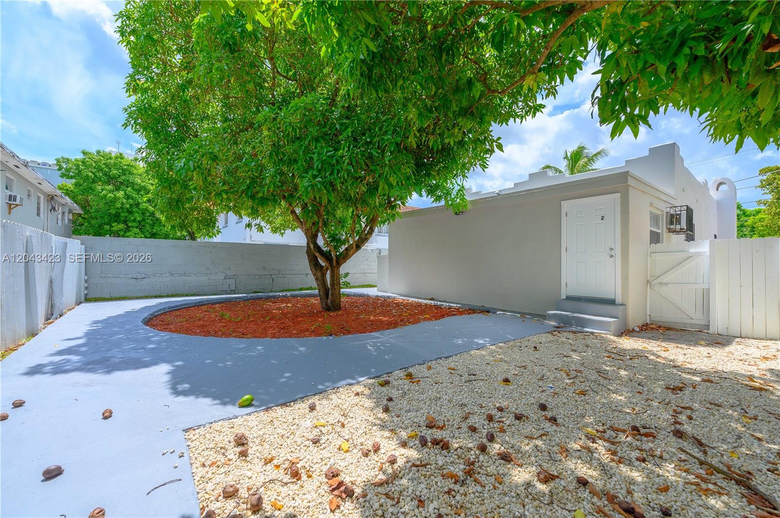 A tree stands in a circular mulch bed surrounded by gray concrete and gravel — 8057 NE 1st Ave # 2, Miami FL 33138, MIAMI, FL