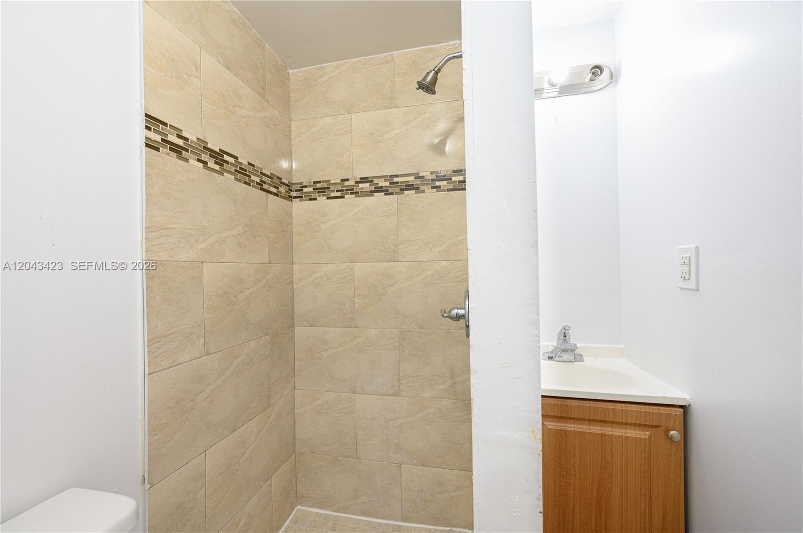 A bathroom features a tiled shower stall next to a vanity with a wooden cabinet — 8057 NE 1st Ave # 2, Miami FL 33138, MIAMI, FL