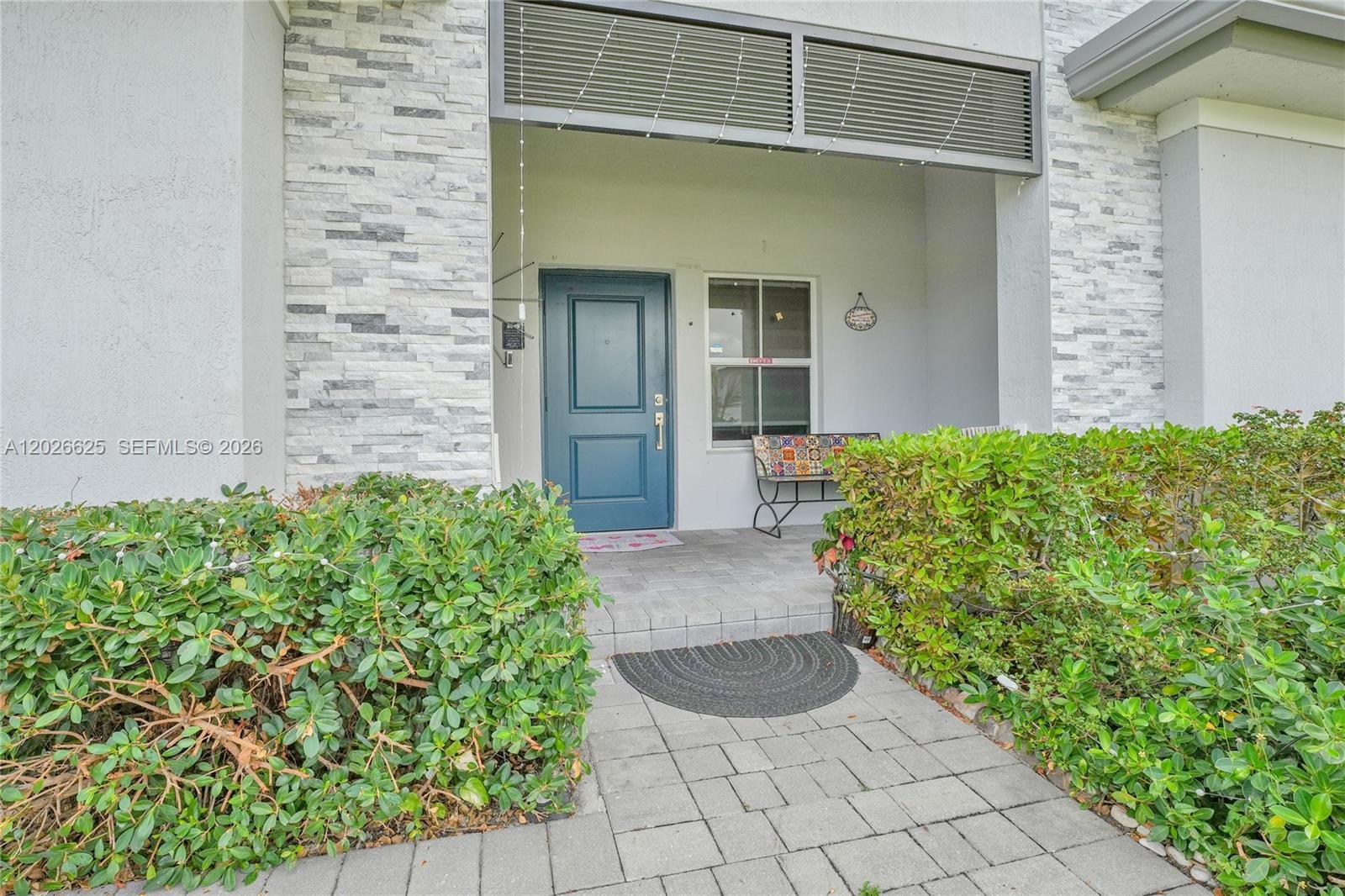 A front entrance features a blue door, stone-tiled walls, and a paved walkway — 21460 SW 127th Pl, Miami FL 33177, MIAMI, FL