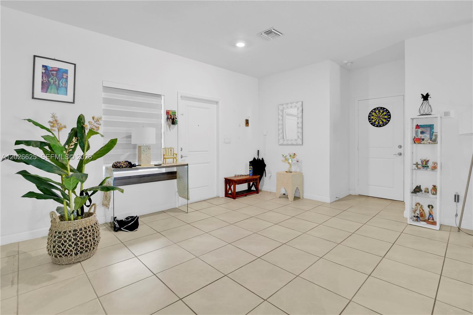 A bright, tiled entryway features a potted plant, a glass console table, and two doors — 21460 SW 127th Pl, Miami FL 33177, MIAMI, FL