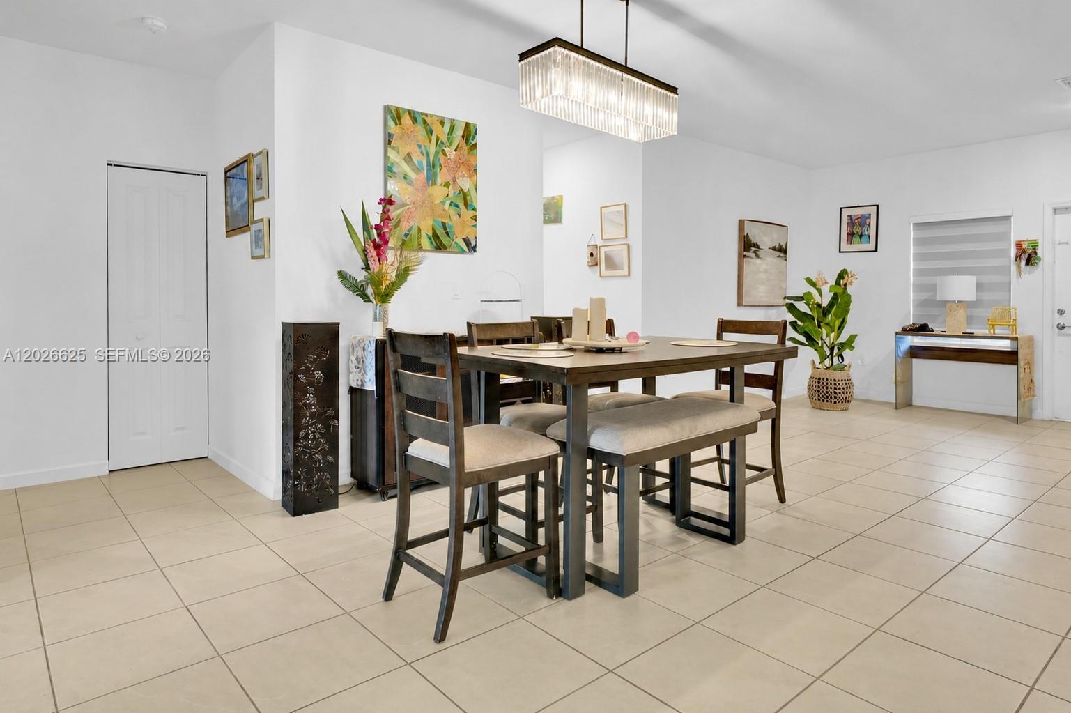 A dining area features a rectangular table with chairs and a bench under a chandelier — 21460 SW 127th Pl, Miami FL 33177, MIAMI, FL