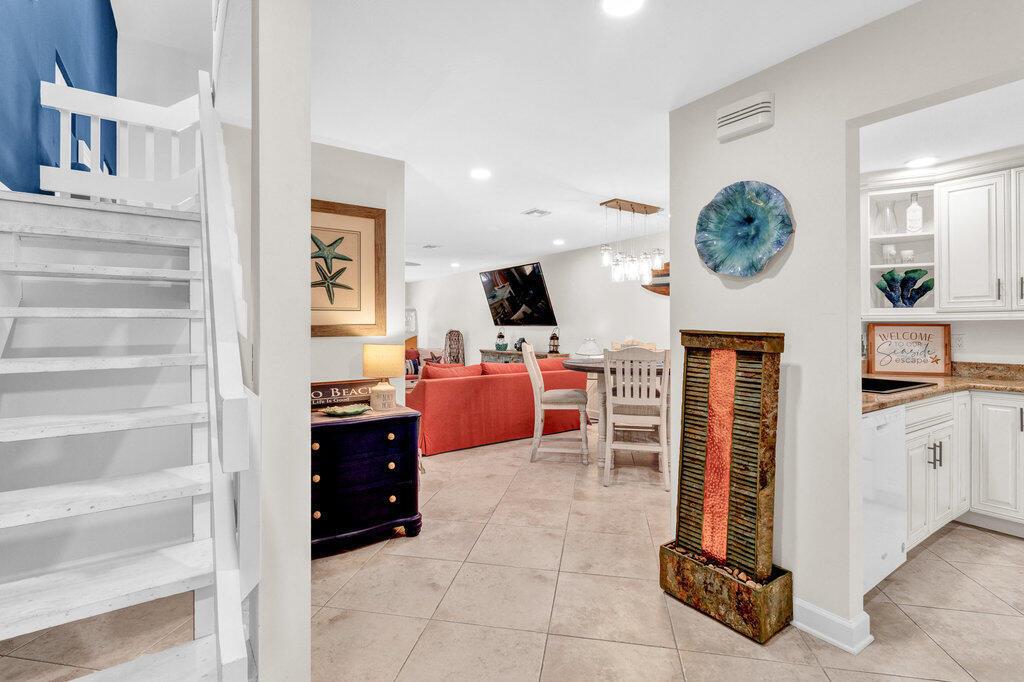 A tiled entryway leads to a living area with a red sofa and white staircase — VERO BEACH, FL