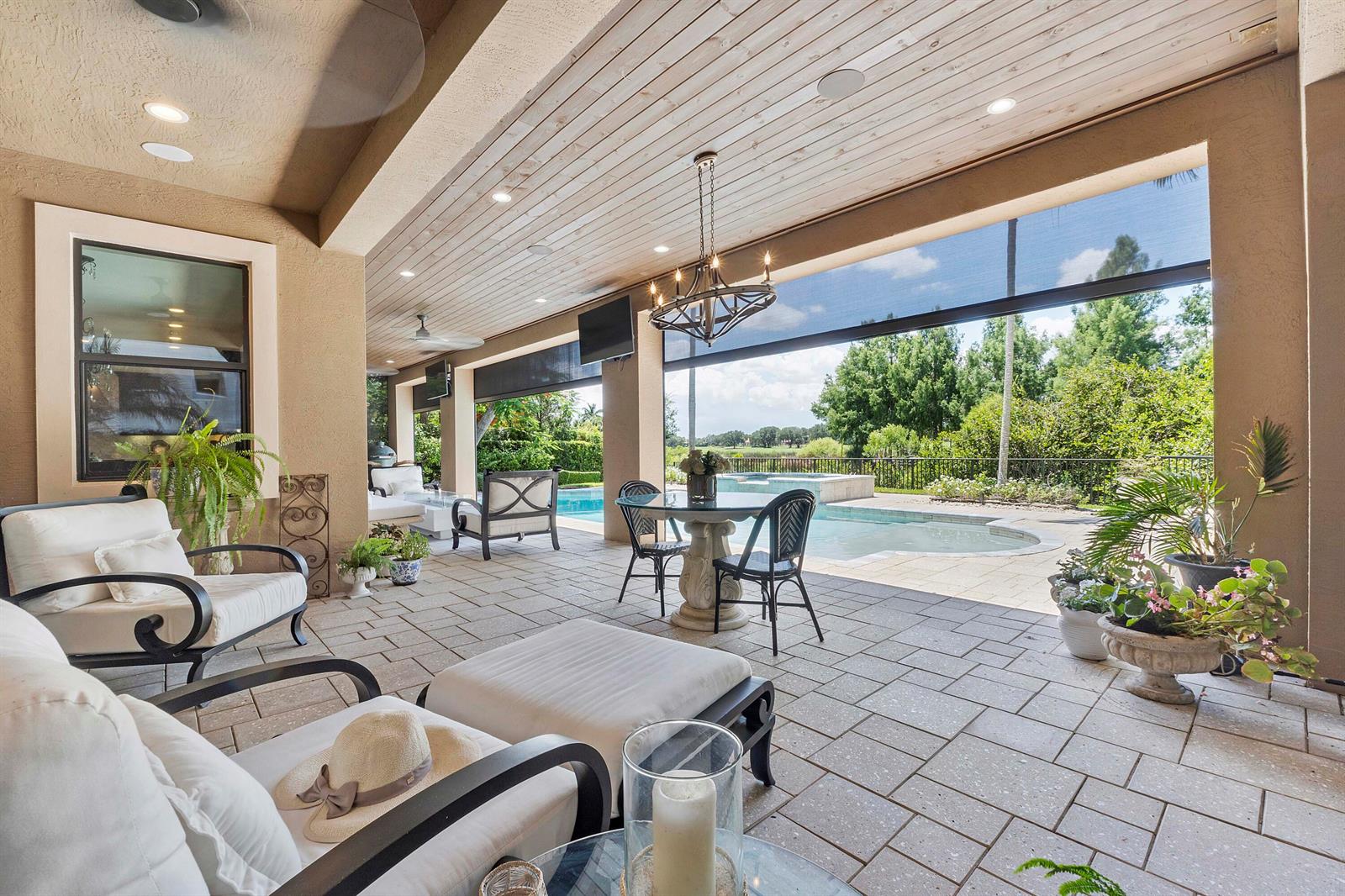 A covered outdoor patio features a dining set, lounge chairs, and a swimming pool view — 10282 Emerson Street, Parkland FL 33076, PARKLAND, FL