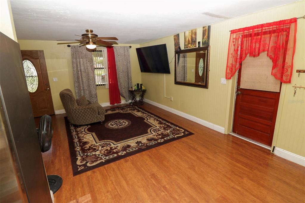 A living room features wood-look flooring, a ceiling fan, a wall-mounted television, and two doors — 3022 VENICE WAY, LAKELAND, FL