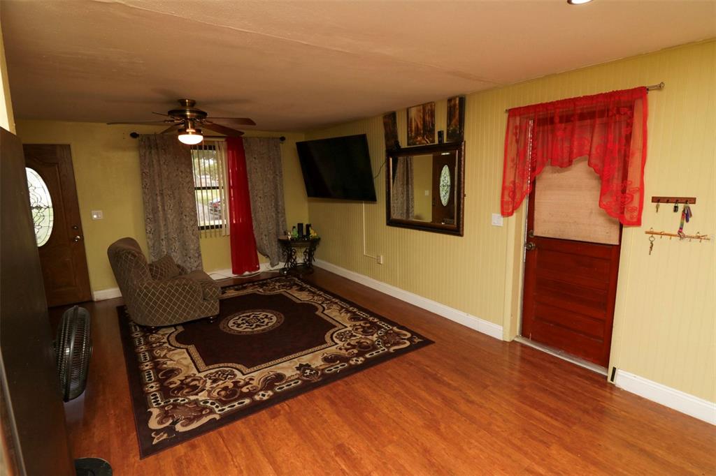 A living room features wood-look flooring, a patterned area rug, a ceiling fan, and doors — 3022 VENICE WAY, LAKELAND, FL