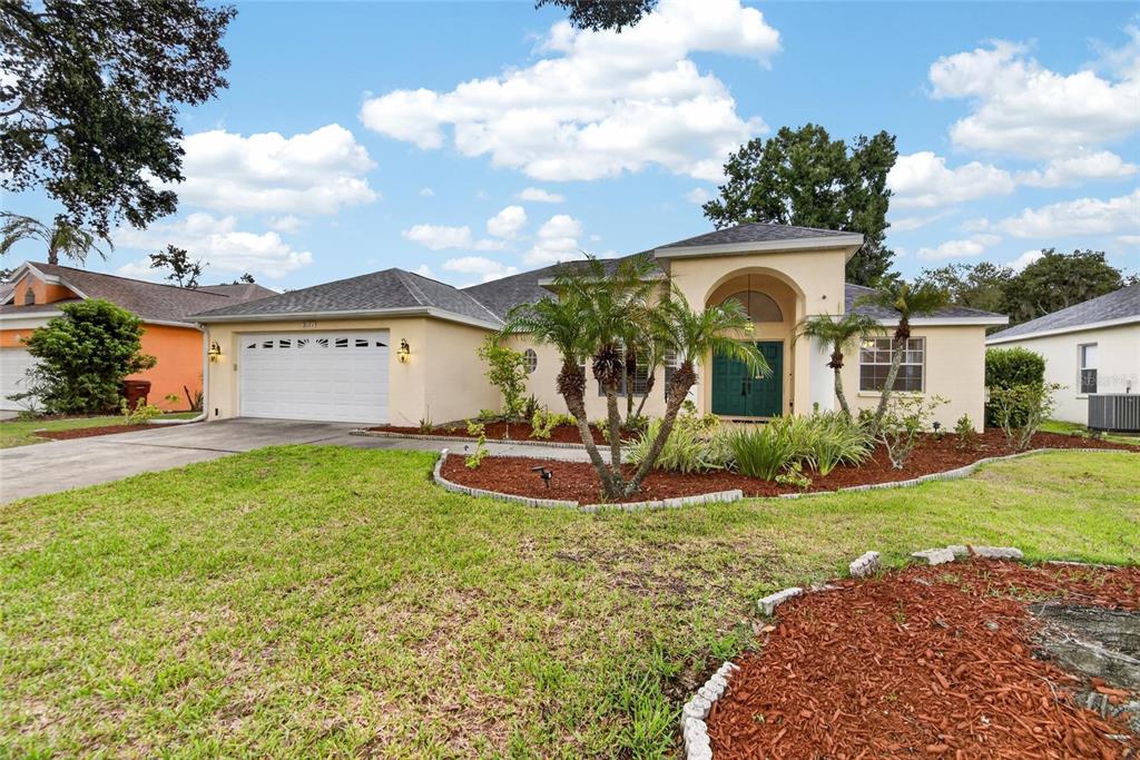 A single-story house with a beige stucco exterior, a two-car garage, and a landscaped yard — 3212 CONCORD WAY, PLANT CITY, FL