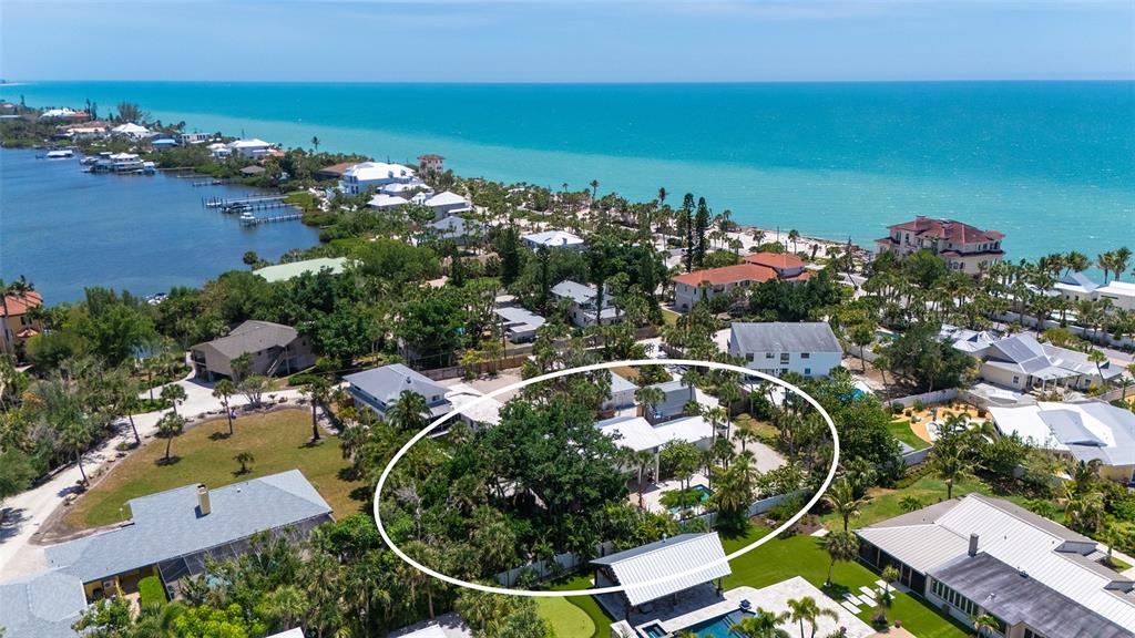 An aerial view shows a coastal residential property surrounded by lush trees and nearby homes — 3708 SANDSPUR LANE, NOKOMIS, FL
