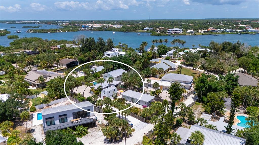 An aerial view shows a residential property with multiple buildings surrounded by lush tropical vegetation — 3708 SANDSPUR LANE, NOKOMIS, FL