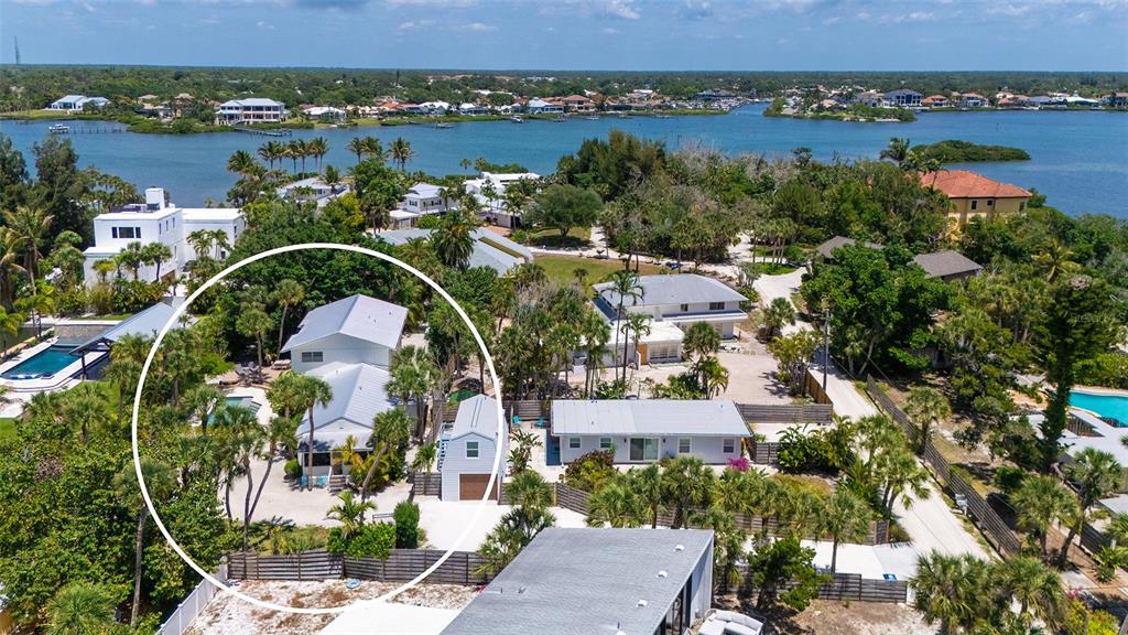 An aerial view shows a white house with a metal roof surrounded by palm trees — 3708 SANDSPUR LANE, NOKOMIS, FL