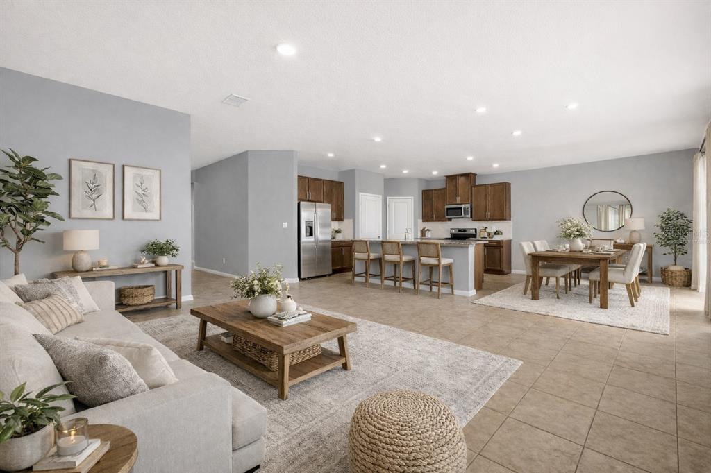 An open-concept living room and kitchen featuring tile floors, wood cabinetry, and neutral decor — 29307 MEADOWCROFT AVENUE, WESLEY CHAPEL, FL