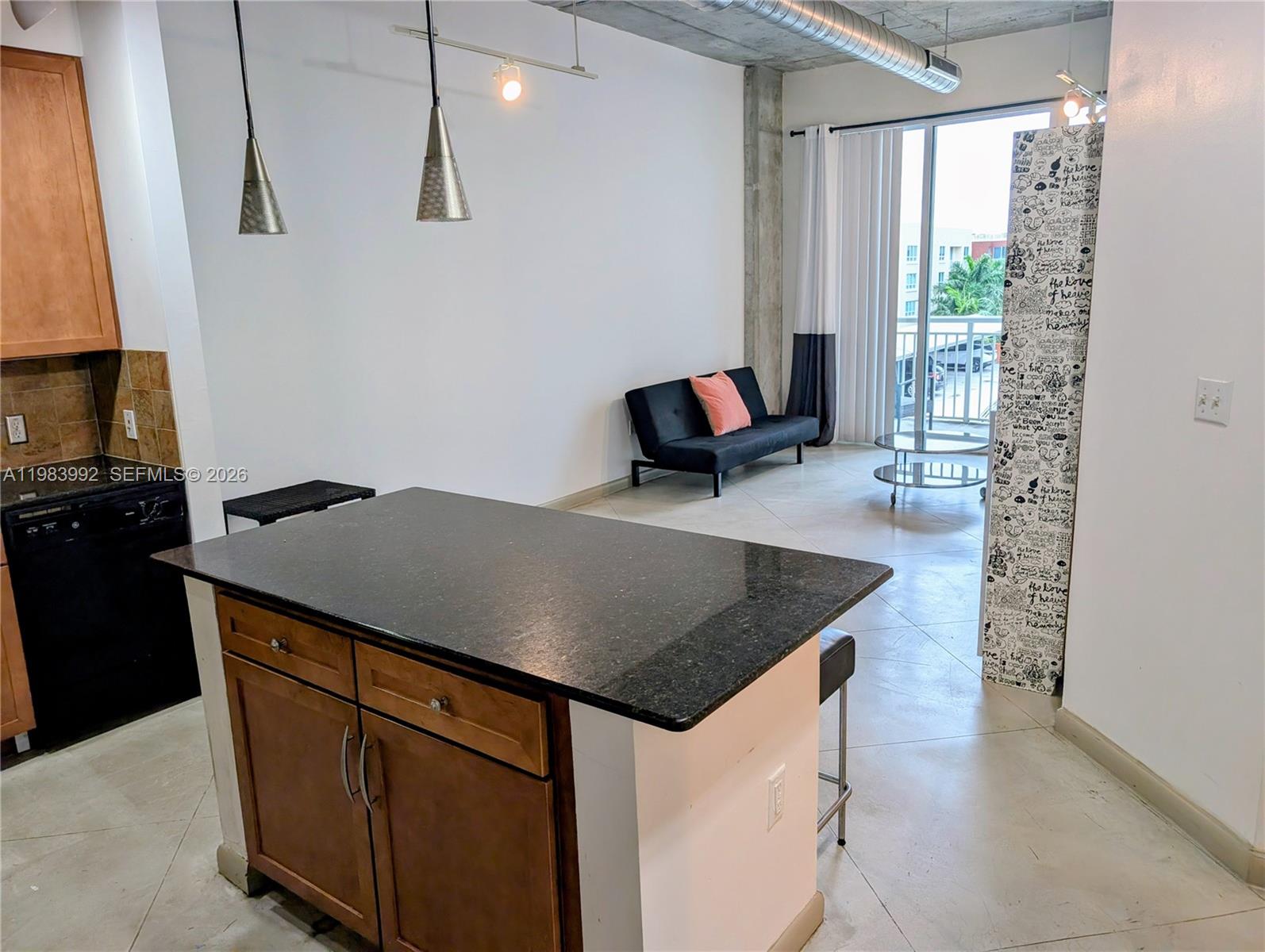 A kitchen island with a dark countertop sits before a living area with a sofa — 2001 Biscayne Blvd # 2521, Miami FL 33137, MIAMI, FL