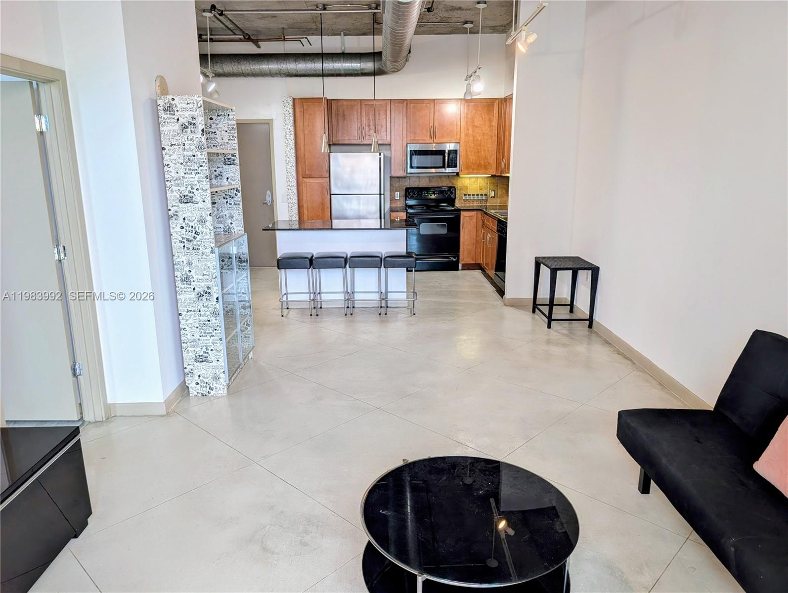 An open-concept kitchen and living area features concrete ceilings, tile floors, and wood cabinetry — 2001 Biscayne Blvd # 2521, Miami FL 33137, MIAMI, FL