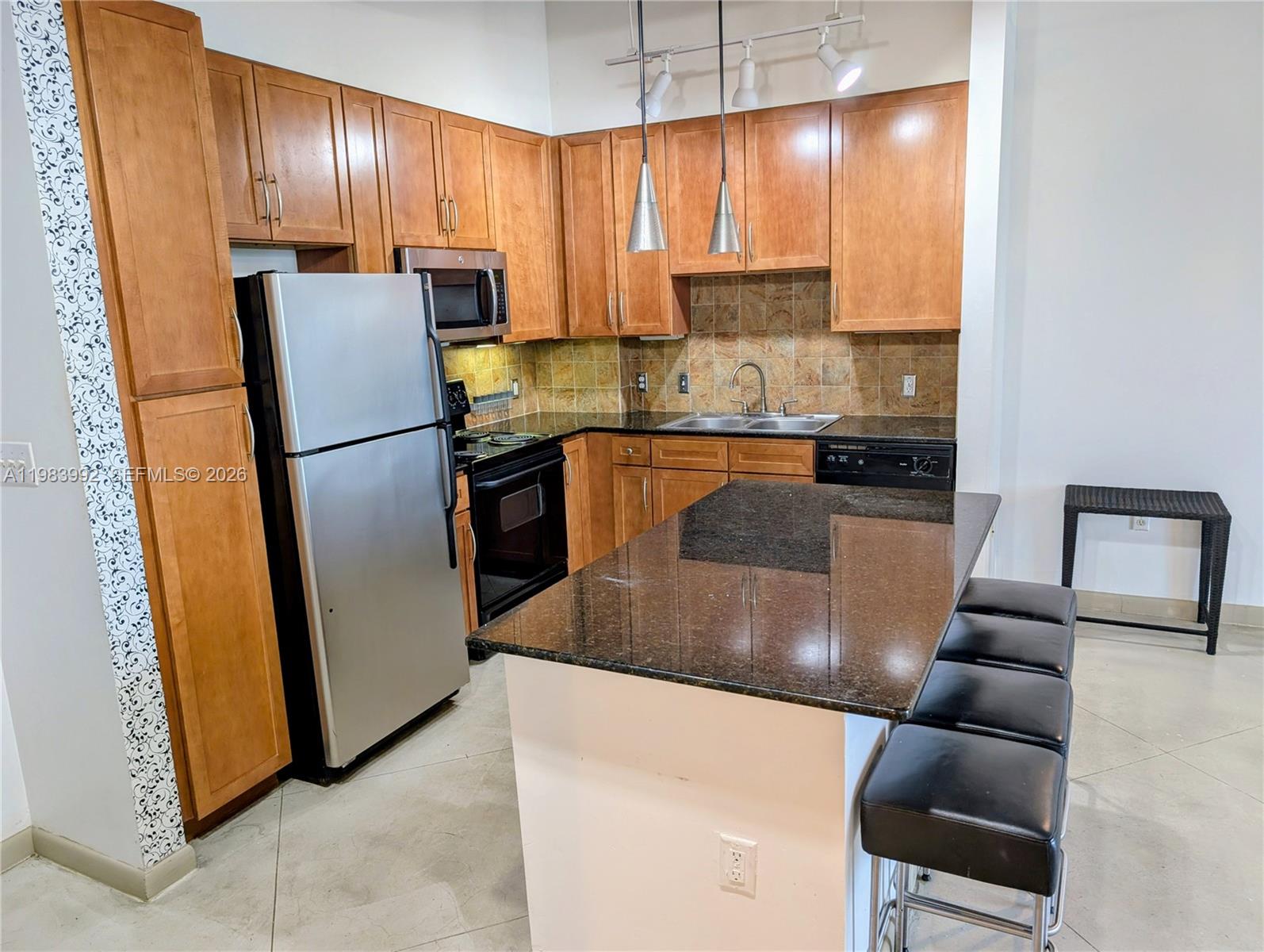 A kitchen features wood cabinets, dark granite countertops, stainless steel appliances, and a breakfast island — 2001 Biscayne Blvd # 2521, Miami FL 33137, MIAMI, FL