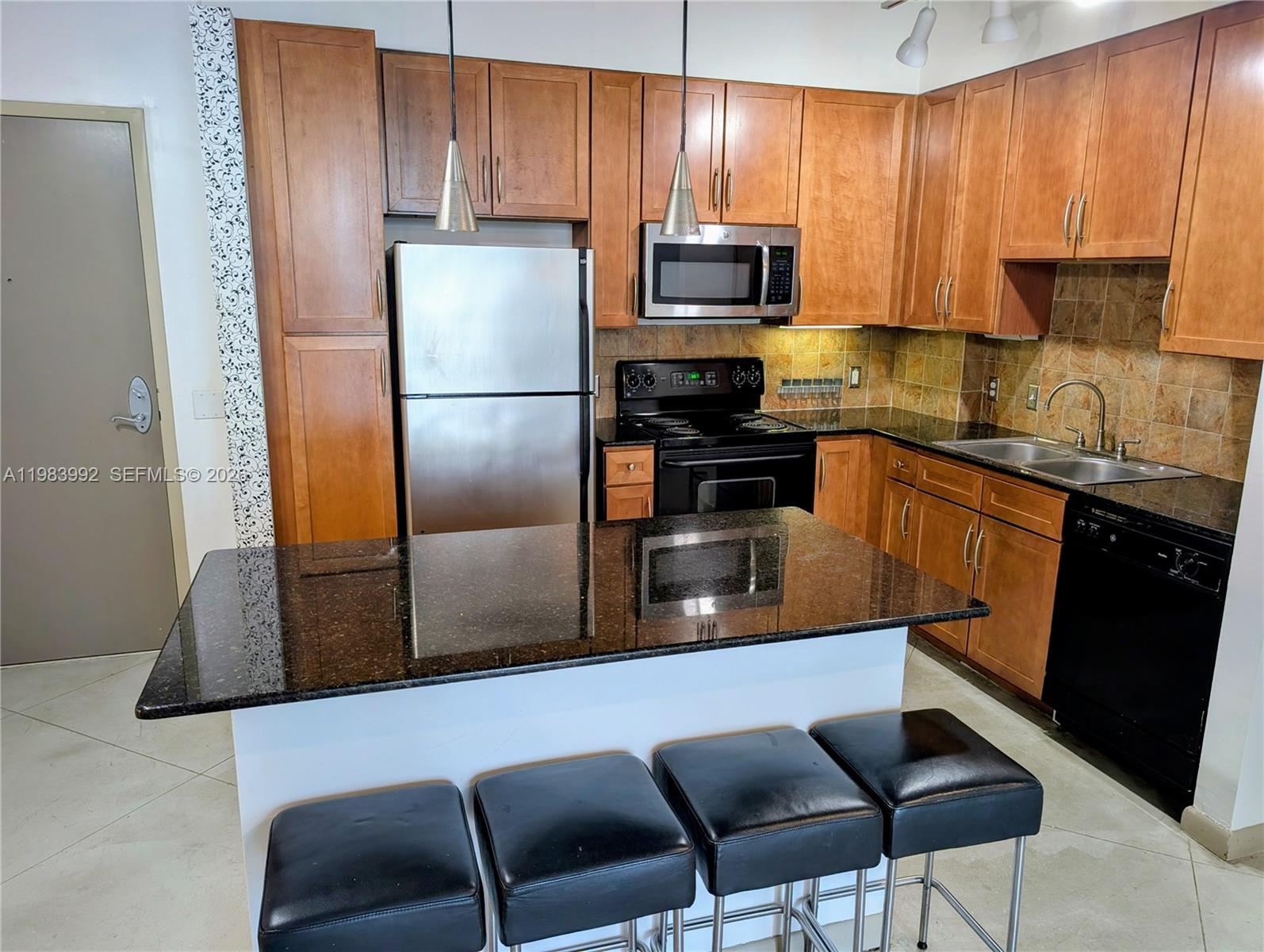 A kitchen features wood cabinets, stainless steel appliances, a granite island, and four black stools — 2001 Biscayne Blvd # 2521, Miami FL 33137, MIAMI, FL