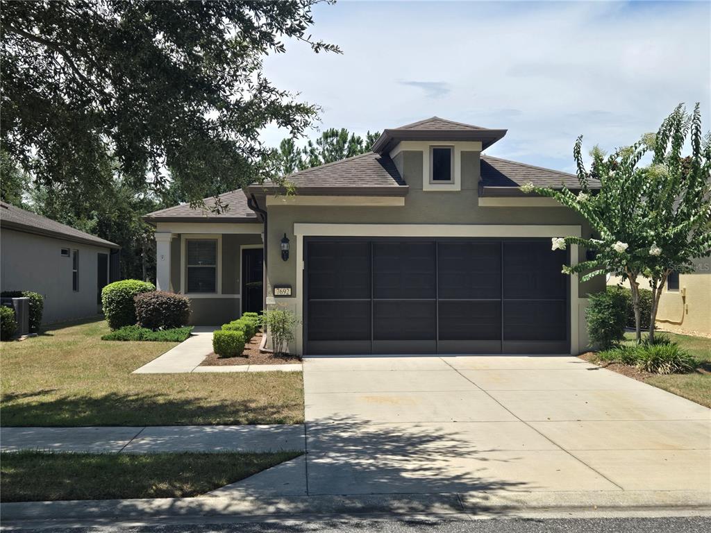 A single-story house with a dark garage door, a concrete driveway, and a small lawn — 7692 SW 94TH CIRCLE, OCALA, FL