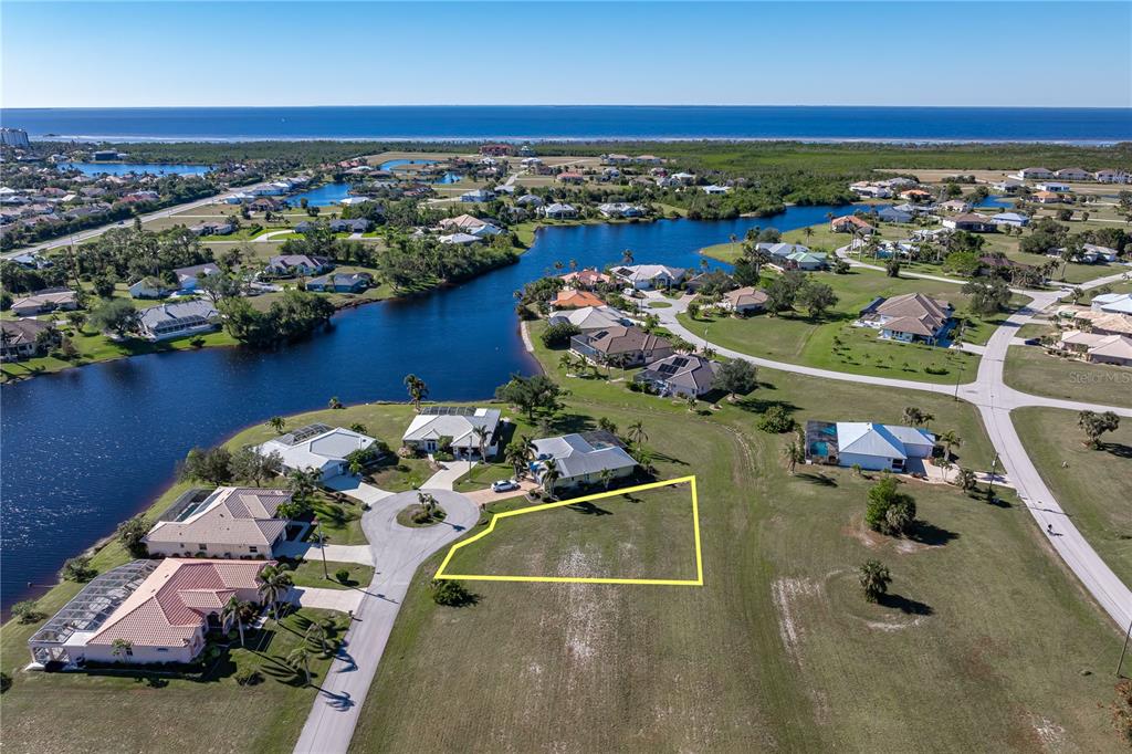 An aerial view shows a vacant residential lot outlined in yellow near a waterfront neighborhood — 17503 MALARKY LANE, PUNTA GORDA, FL