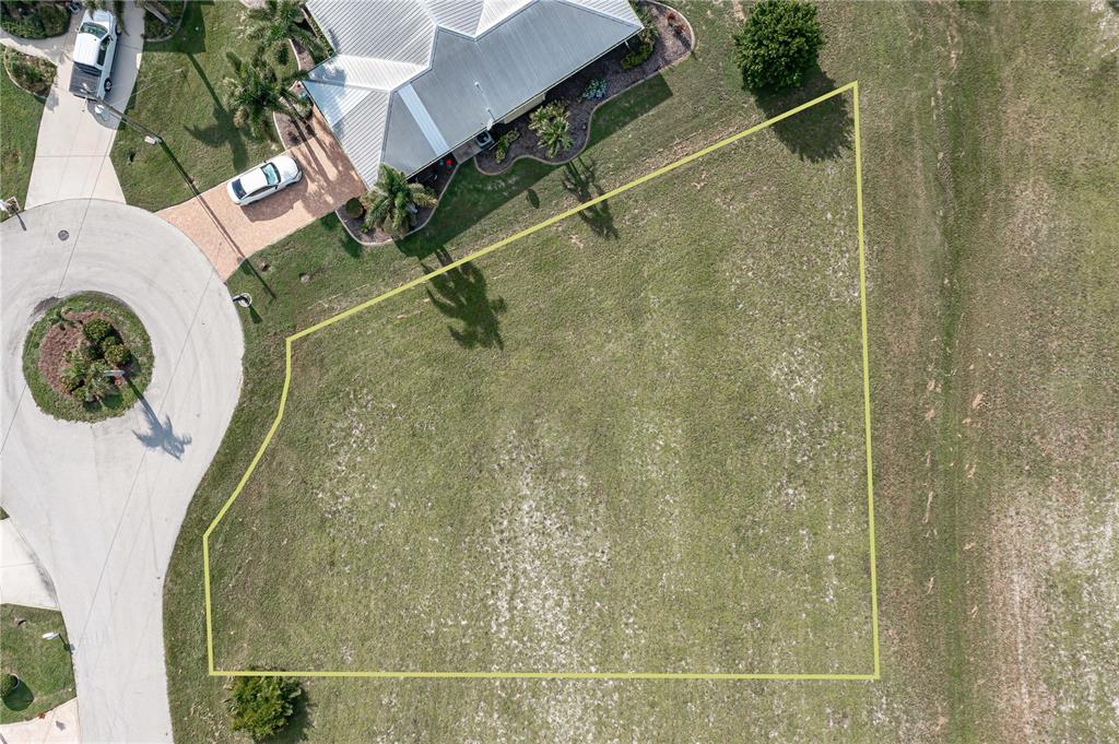 An aerial view shows a vacant residential lot outlined in yellow next to a house — 17503 MALARKY LANE, PUNTA GORDA, FL