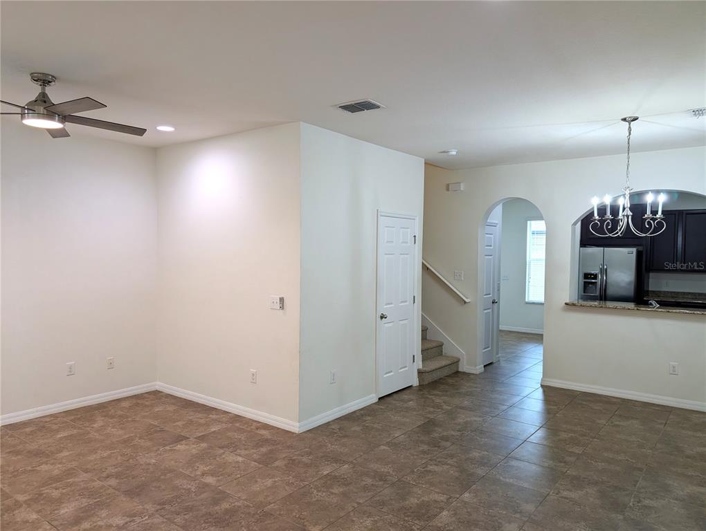An open-concept room features tile flooring, a ceiling fan, a staircase, and a kitchen pass-through — 14161 STOWBRIDGE AVENUE, TAMPA, FL